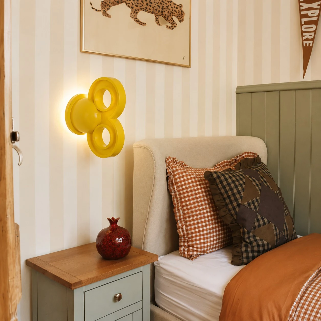 Yellow wall light beside a bed in a warm bedroom