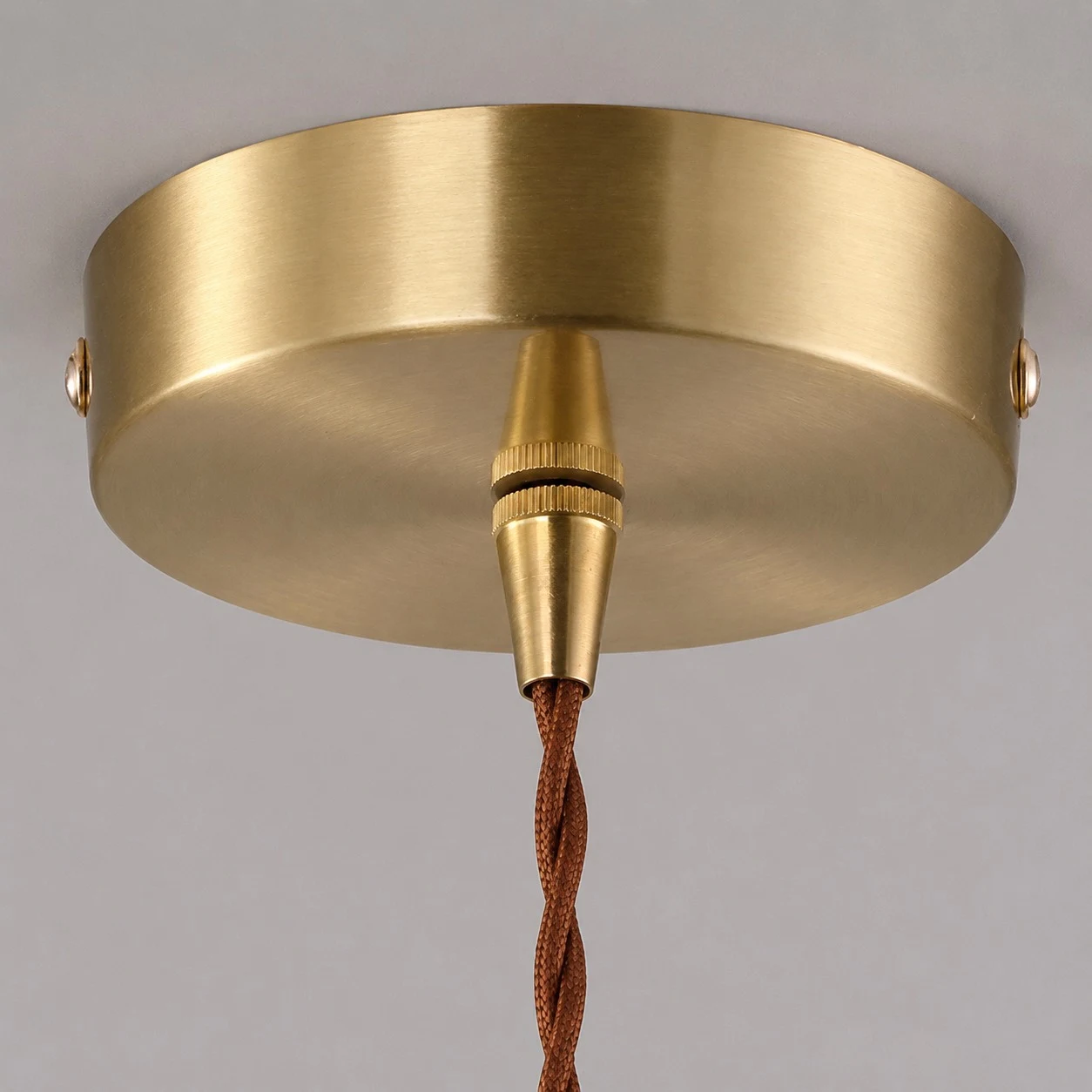 Warm lit glass shade detail on brass pendant light
