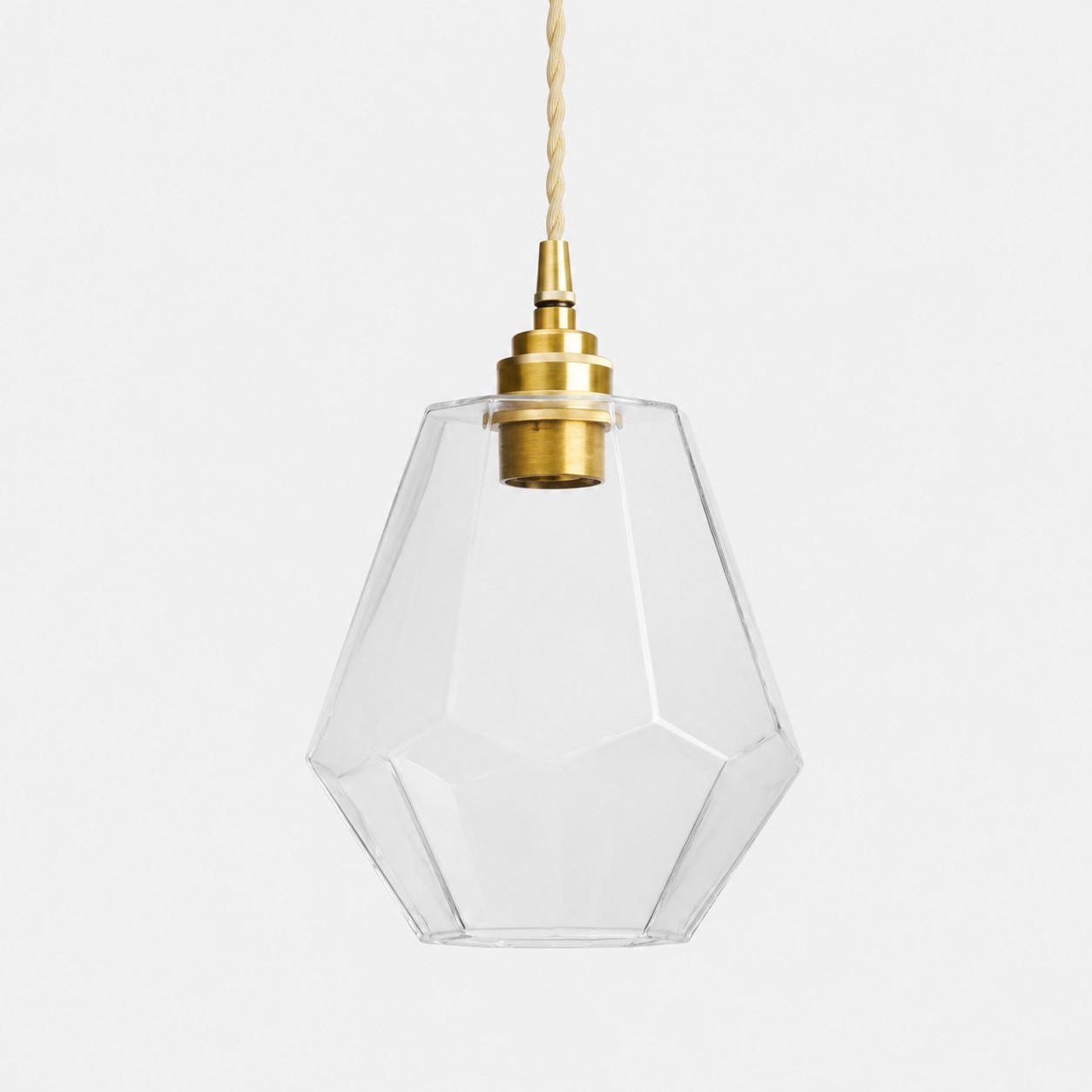 Clear faceted glass pendant light with antique brass holder on white background