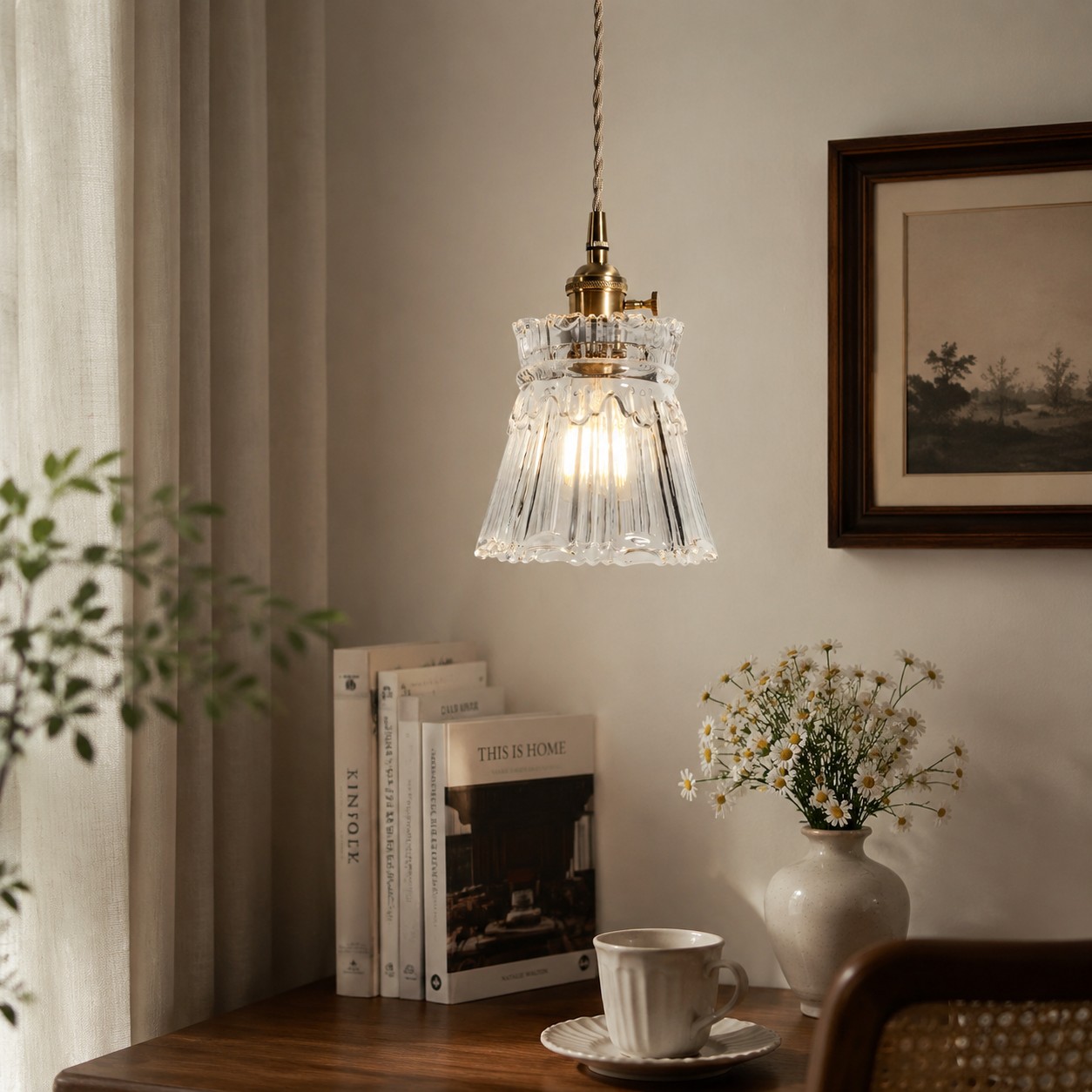 Style M ornate clear glass pendant beside books and tableware