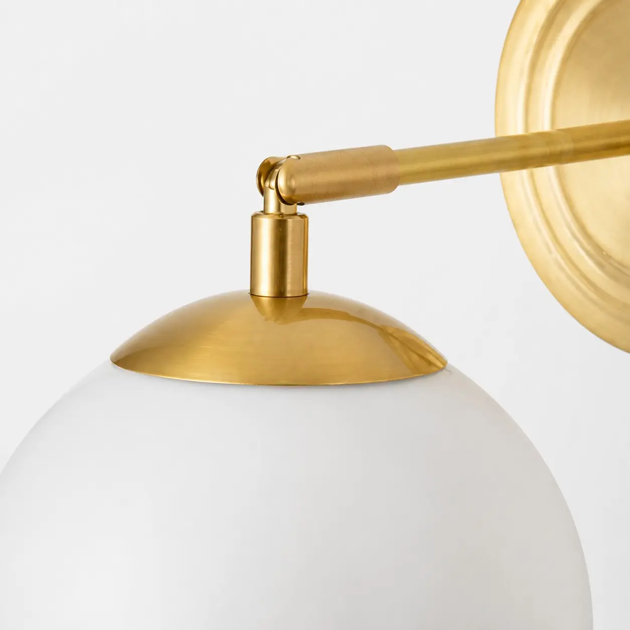 Close view of the gold arm and milk glass shade connection