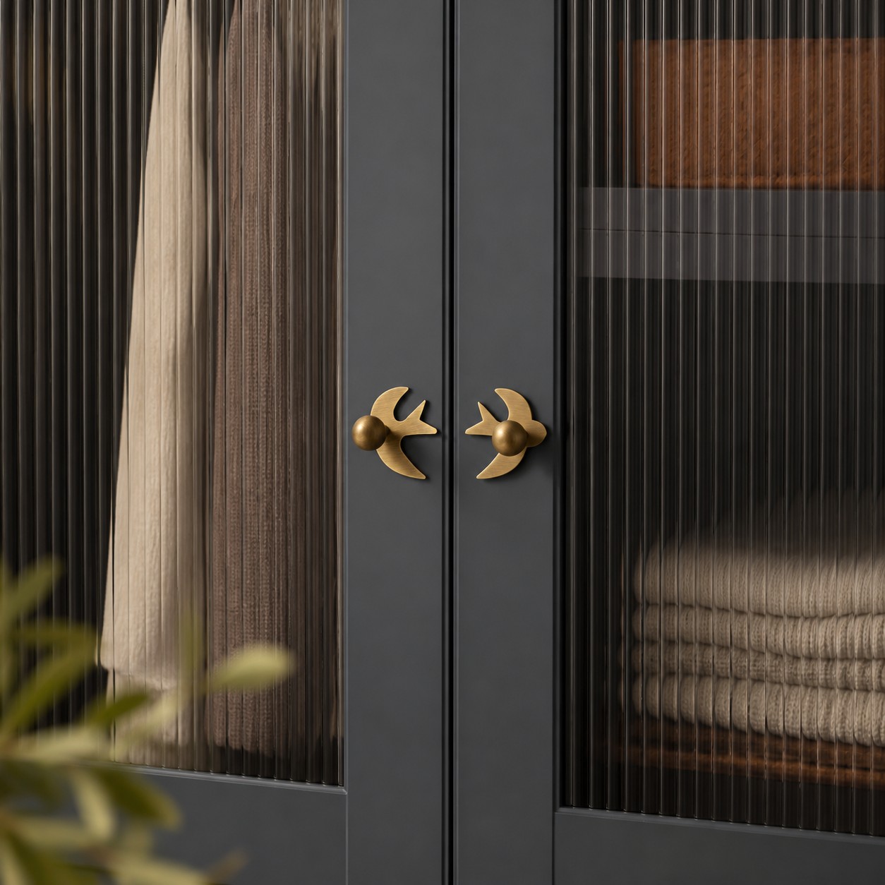 Mirrored antique brass swallow handles on a dark cabinet