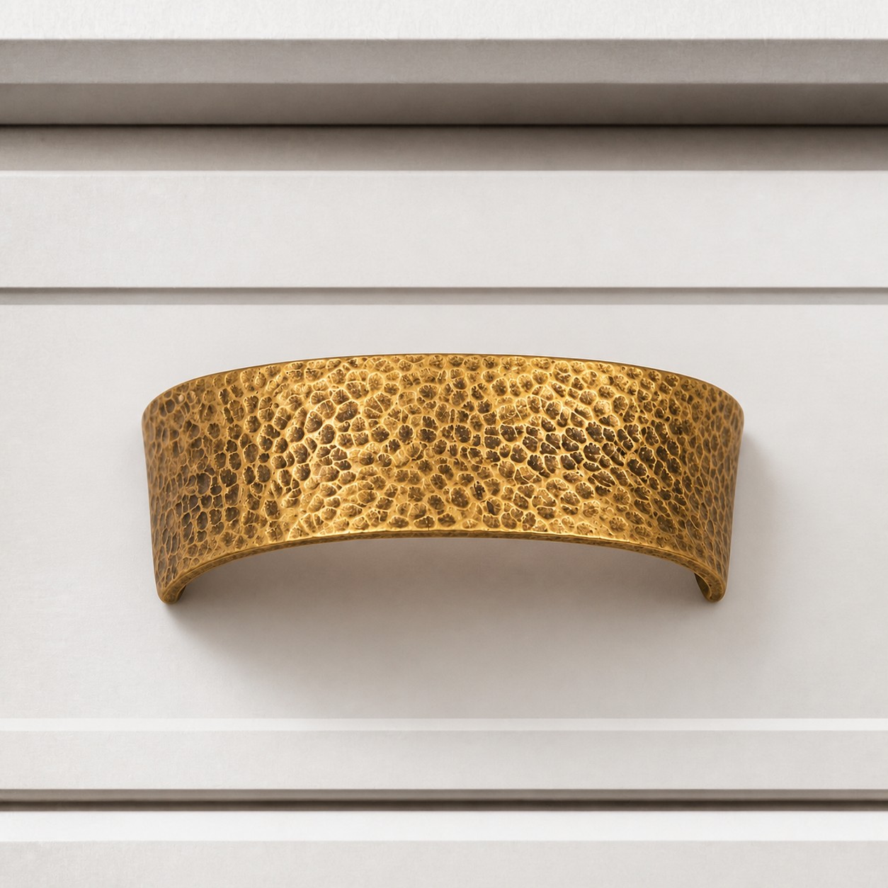 Hammered brass cabinet pull on white drawer front