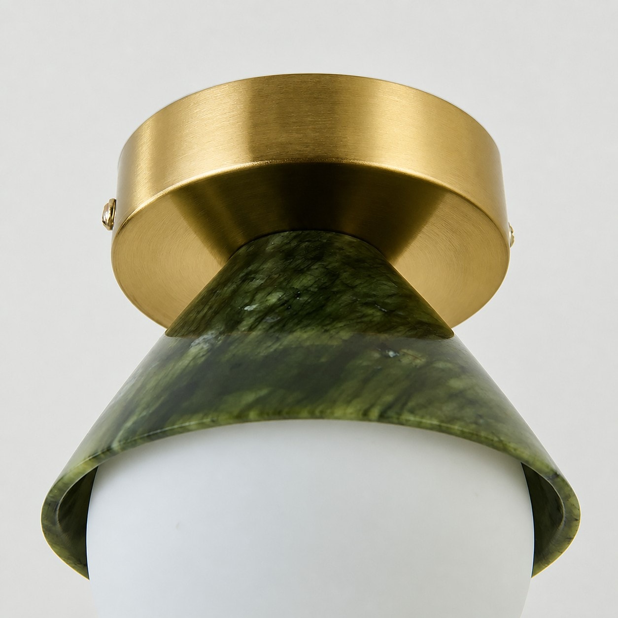 Close-up of brushed metal ceiling canopy and curved green shade