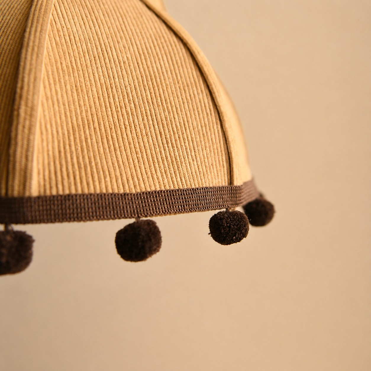 Ochre ribbed fabric and pom-pom trim detail