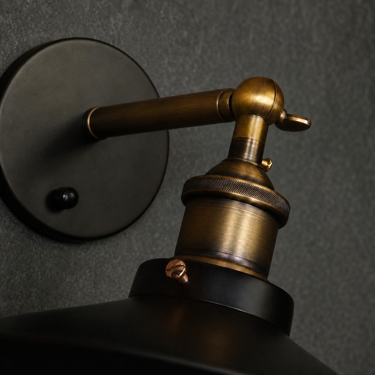 Close-up of round wall plate, metal arm, and adjustable joint
