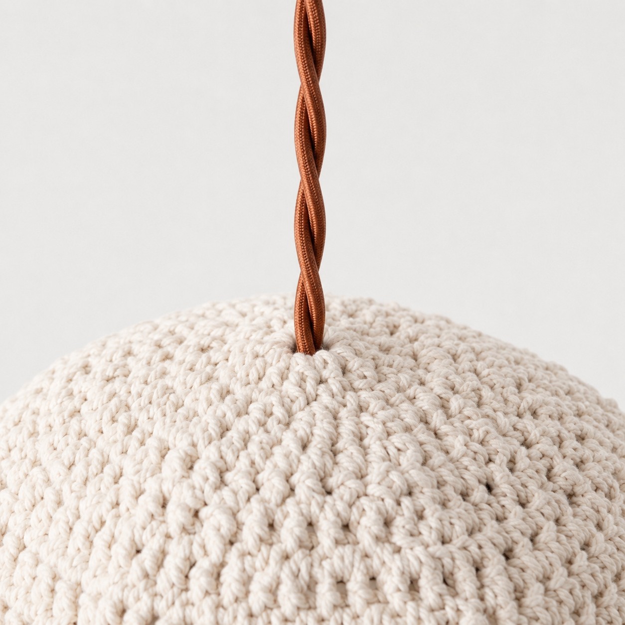 Close-up of twisted brown pendant cord entering the ivory handwoven shade