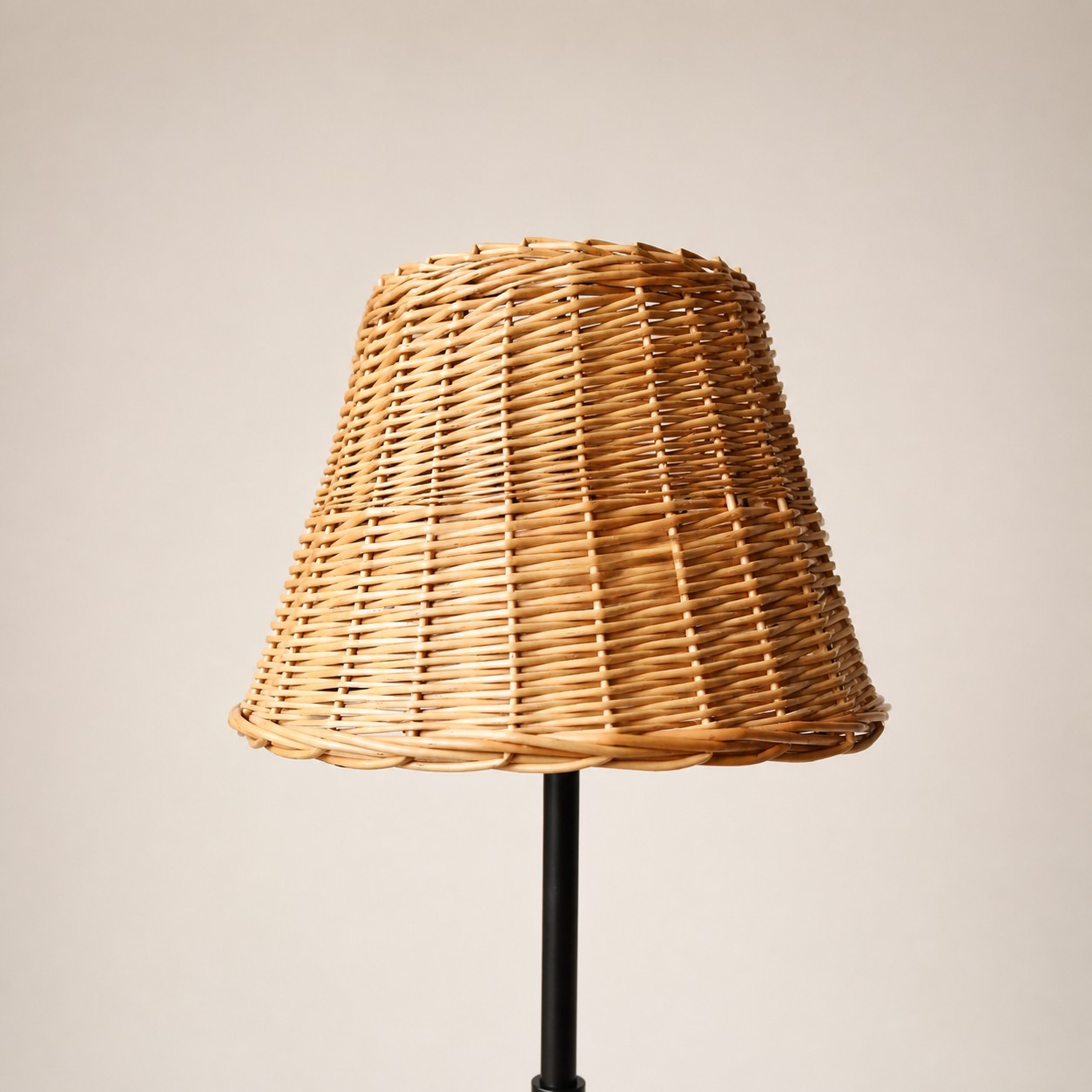 Rattan lampshade on slim black floor lamp stand